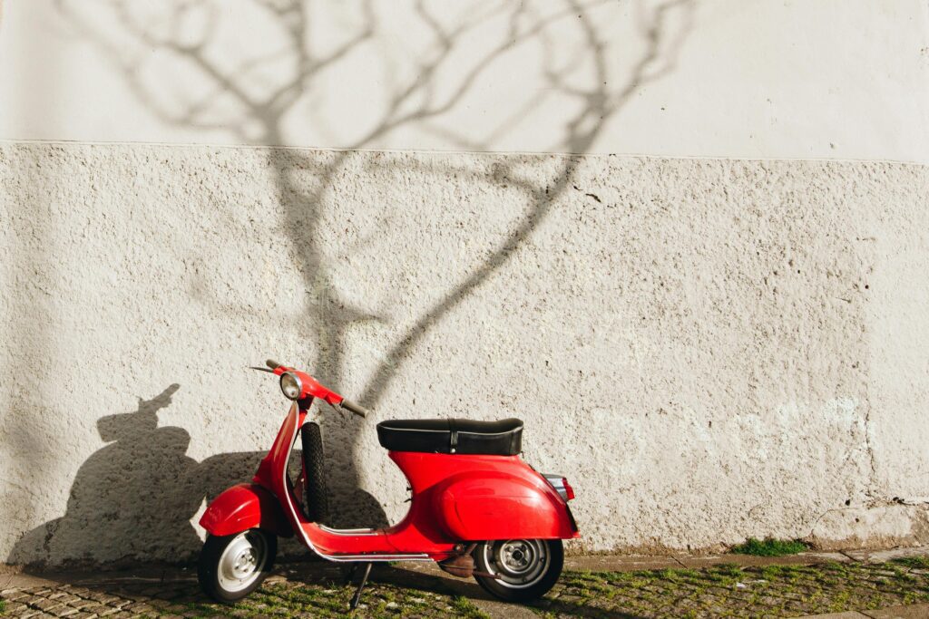 A vibrant red vintage scooter parked against a textured wall in Porto, Portugal.